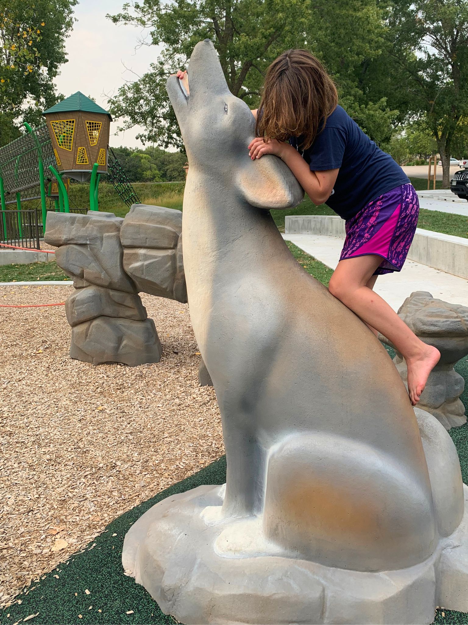 A girl limbs on a wolf sculpture at the Platte River State Park playground