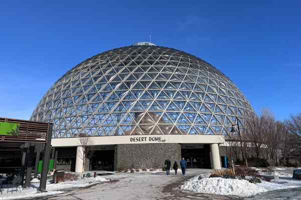Three people walk to the Desert Dome at Omaha's Zoo in the winter, with snow visible on the ground