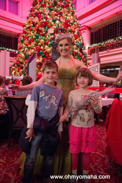A costumed princess and kids in front of the Christmas tree in the Walnut Room