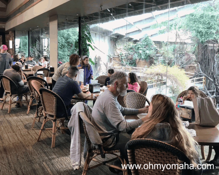 Diners at TreeTops Restaurant sitting at tables by the windows overlooking the indoor rainforest at Omaha's zoo