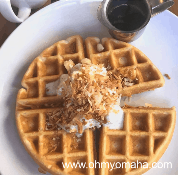 Plate of belgian waffle with whipped cream on top