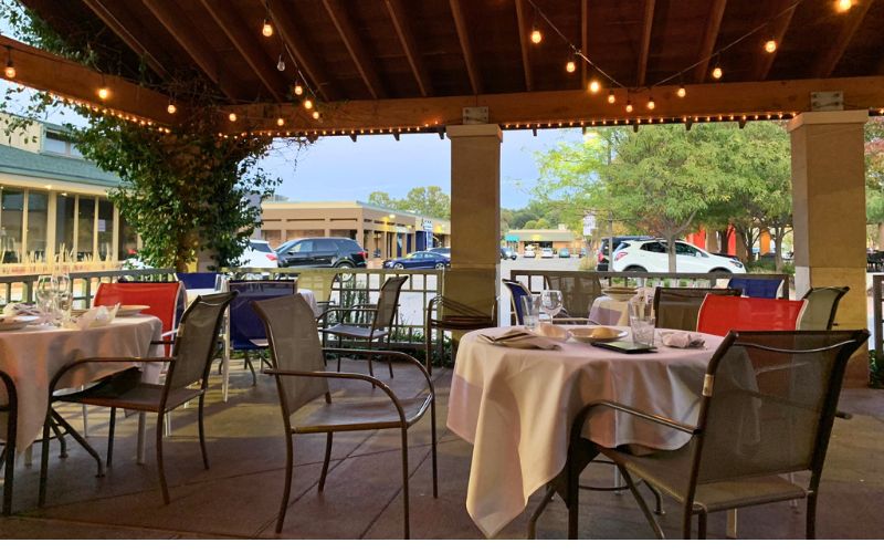 The patio at Pasta Amore with cloth-covered tables and stringed lights