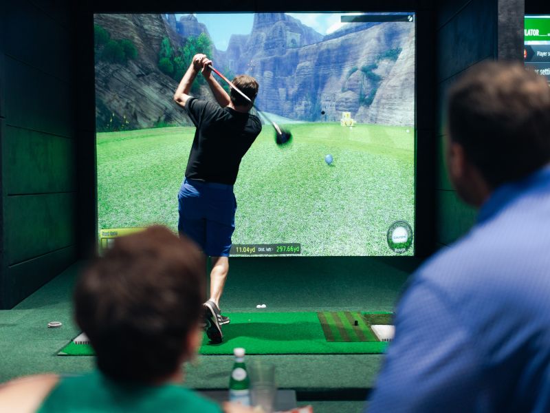 A golfer swings indoors at Beyond Golf Bar + Kitchen in LaVista