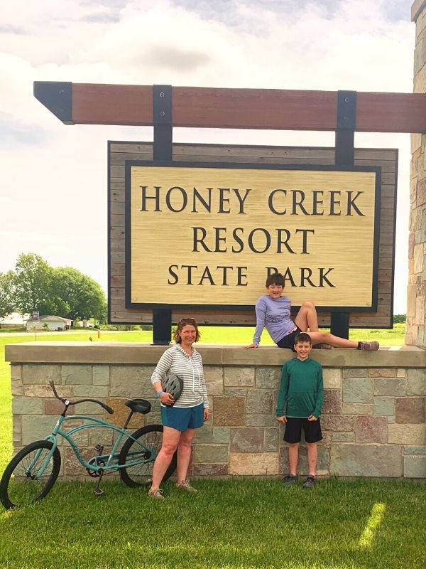 Kim and kids in front of Honey Creek Resort sign in Iowa