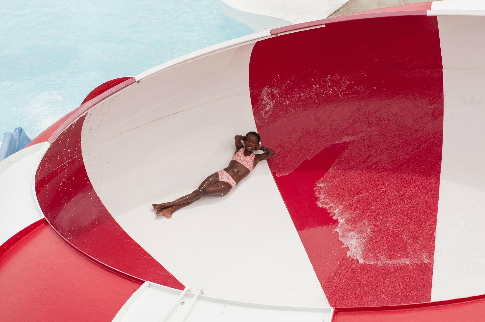 A girl slides down a red and white slide at King's Pointe