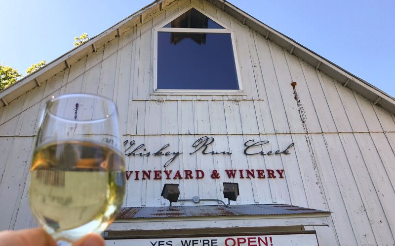 A glass of white wine in front of Whiskey Run Creek Winery in Brownville 