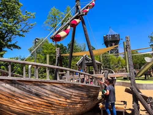 A man holds a child up to a pirate ship at The Gathering Place in Tulsa