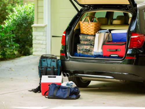 A trunk of a car packed with suitcases, coolers and bags, ready for a road trip.