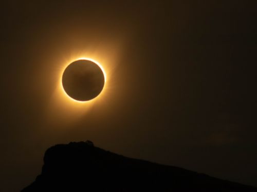 A photo of a total solar eclipse over a rocky cliff