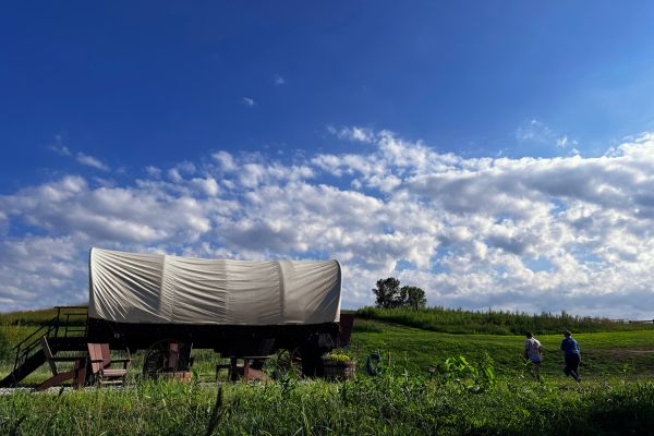 Two people walk up to the covered wagon at Best Nest Farm in Iowa