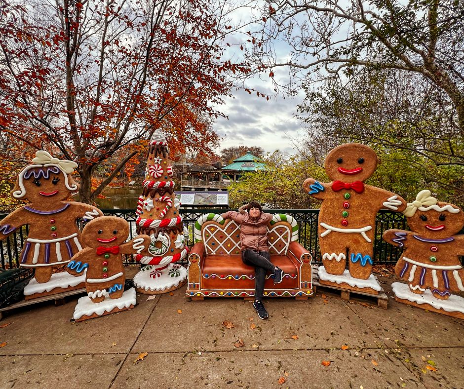 A girl sits on a gingerbread couch surrounded by gingerbread people in holiday a display at Saint Louis Zoo