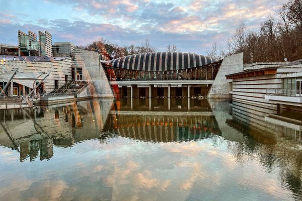 Crystal Bridges Museum of American Art behind a pool of water reflecting the museum and poofy clouds