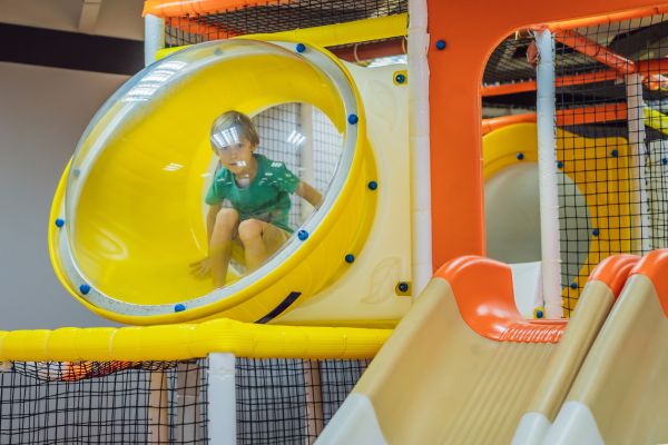 An indoor playground with a bubble window and a small kid looking out from inside it