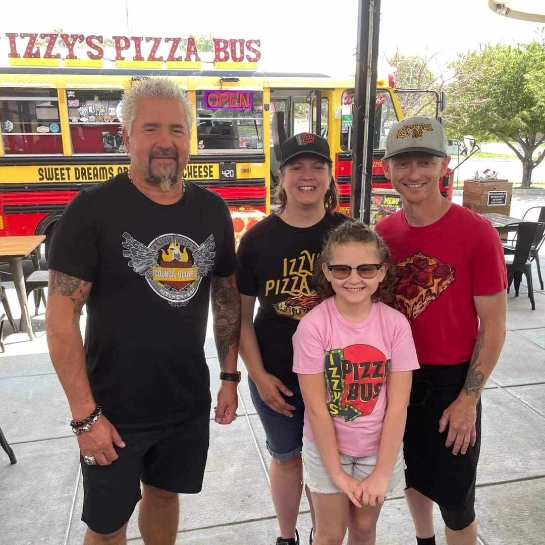 The owners of Izzy's Pizza Bus with Guy Fieri, the host of 