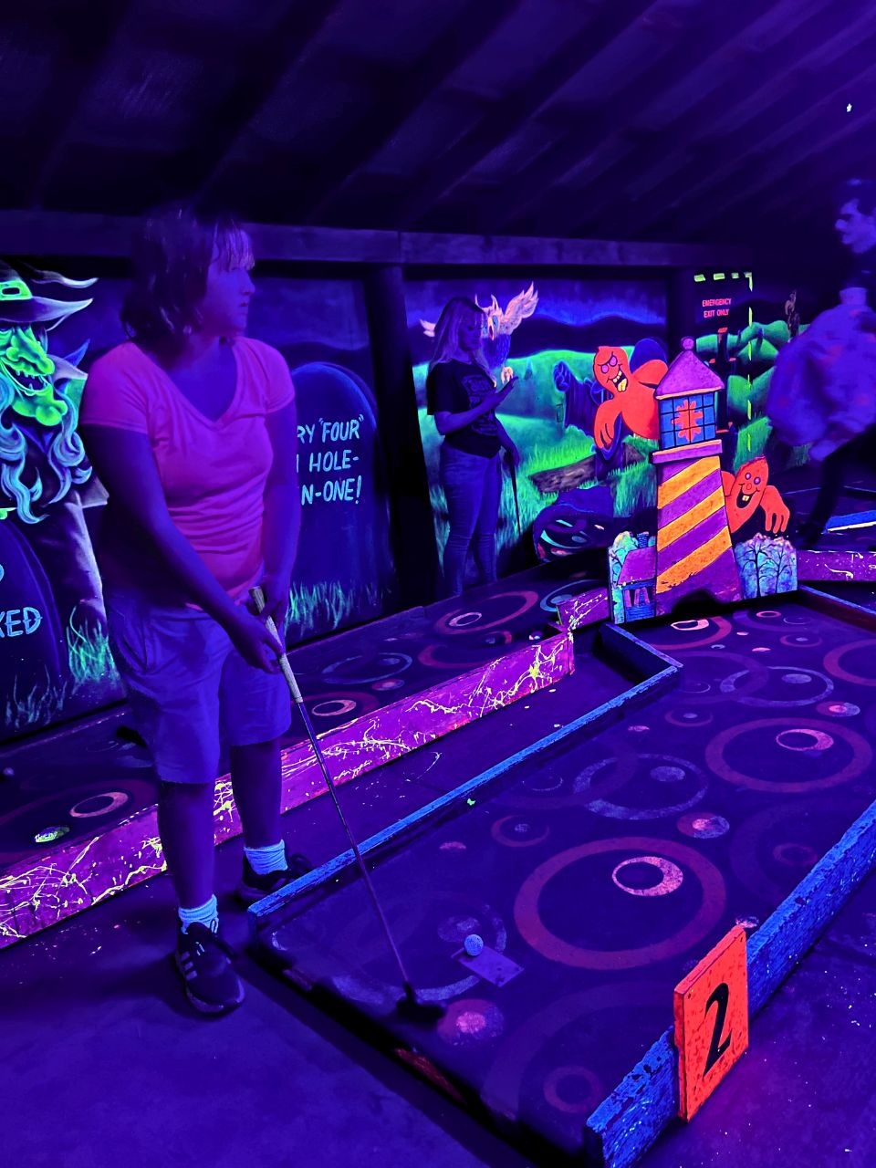 A girl gets ready to putt in the blacklight putt putt course inside Vala's Pumpkin Patch