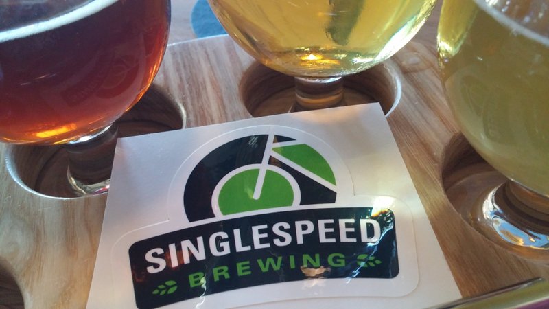 A Singlespeed Brewing sticker surrounded by a flight of beer