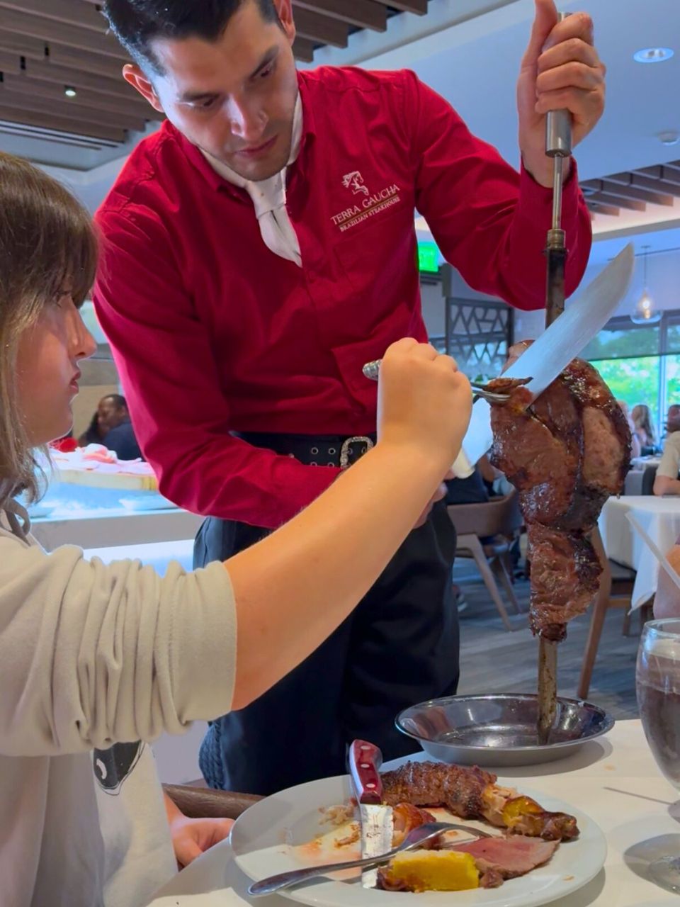 A girl gets a piece of steak from a serve at Terra Gaucha Brazilian Steakhouse