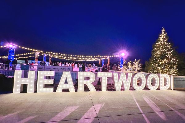 A sign of lights that reads Heartwood with an ice skating rink in the background