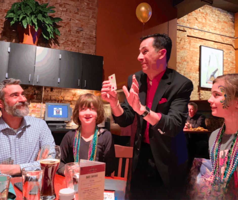 A magician at the table during Mardi Gras festivities at Upstream Brewing Co.