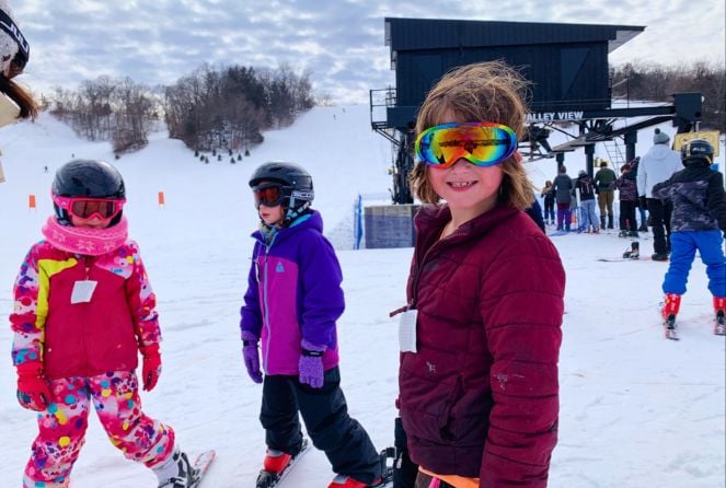 Three girls stand on skis at the base of Seven Oaks Recreation in Boone, Iowa.