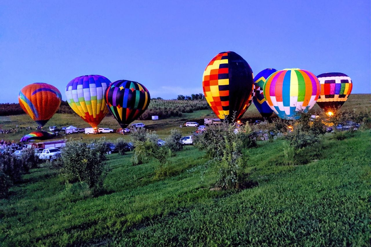 Hot air balloons glow in the dusk at Ditmars Orchard and Vineyard in Council Bluffs