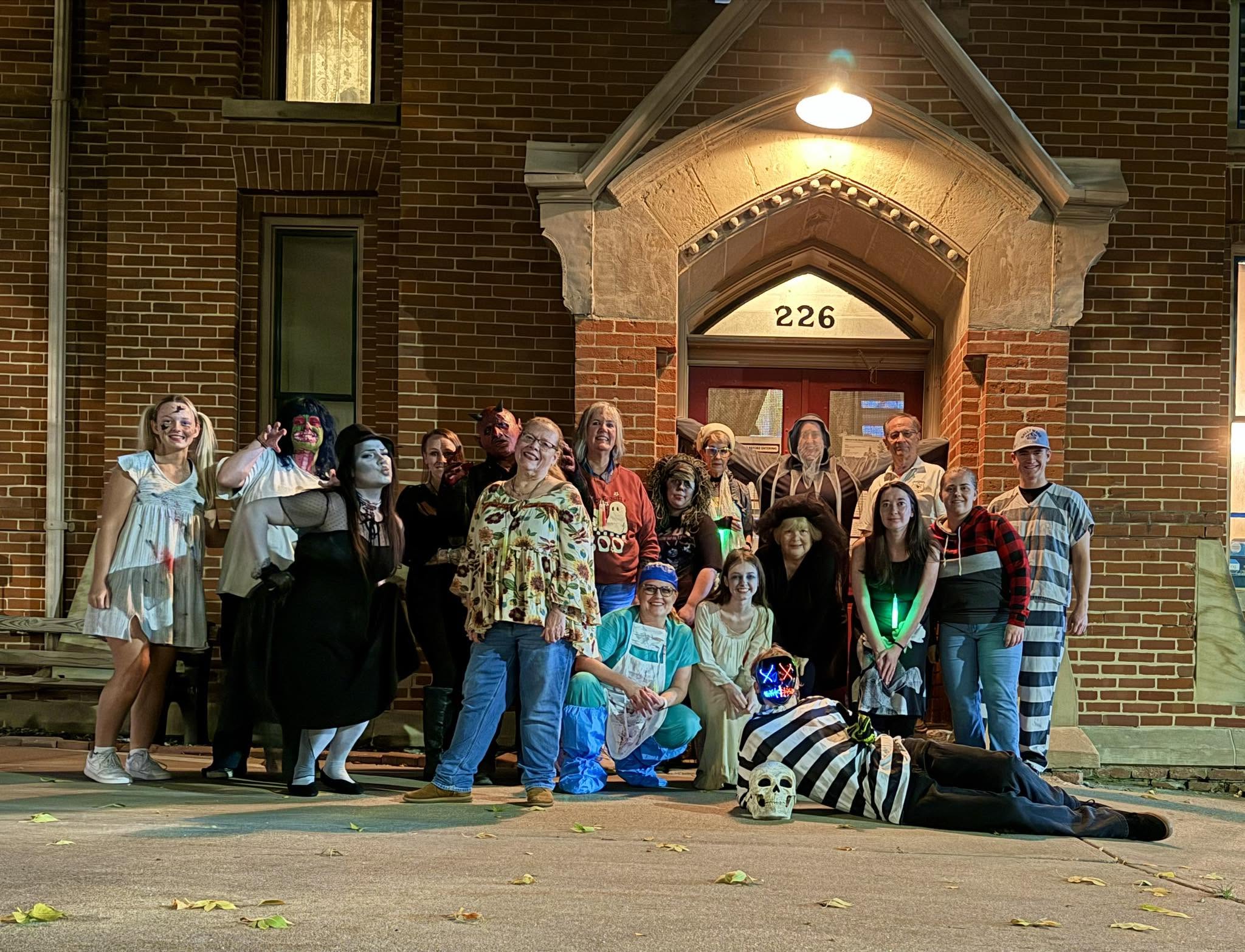 A group of people in costumes stand in front of Squirrel Cafe Jail
